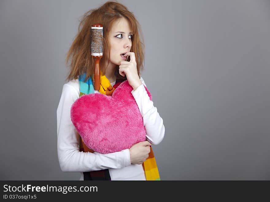 Sad red-haired girl with comb. Studio shot.