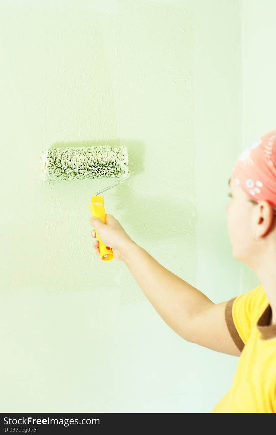 Young woman painting the wall with green paint. Young woman painting the wall with green paint