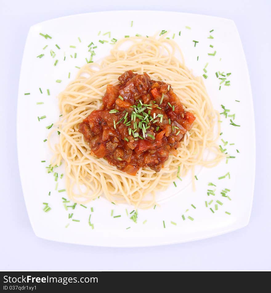 Spaghetti bolognese on a plate decorated with some chives