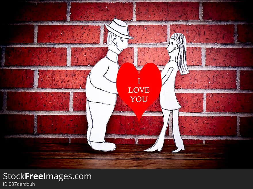 A couple drawn on paper and photographed on a wood floor in front of a brick wall. A couple drawn on paper and photographed on a wood floor in front of a brick wall.