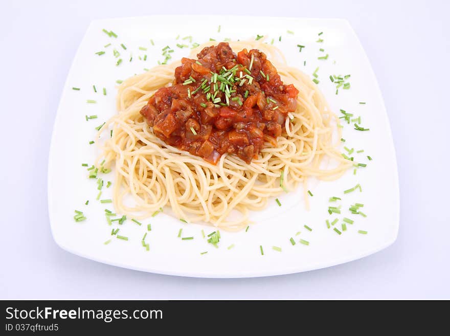 Spaghetti bolognese on a plate decorated with some chives