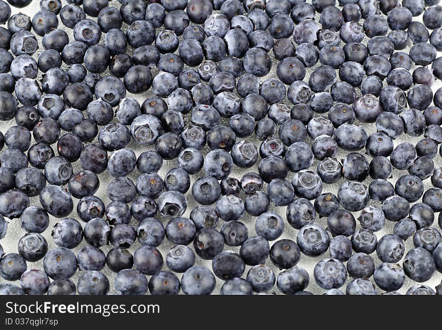 Layer of fresh, organic blueberries on a layer of flat crystalized glass. Layer of fresh, organic blueberries on a layer of flat crystalized glass.