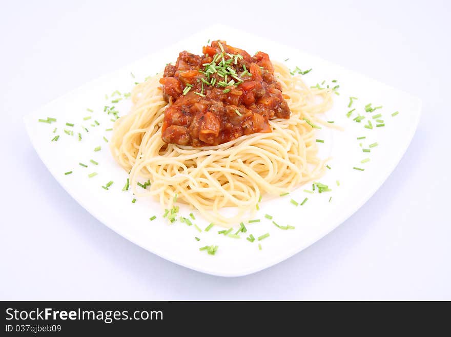 Spaghetti bolognese on a plate decorated with some chives