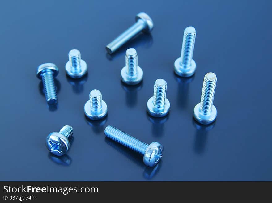 Many metal bolts on a grey background