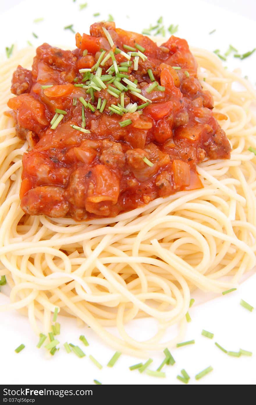 Spaghetti bolognese on a plate decorated with some chives