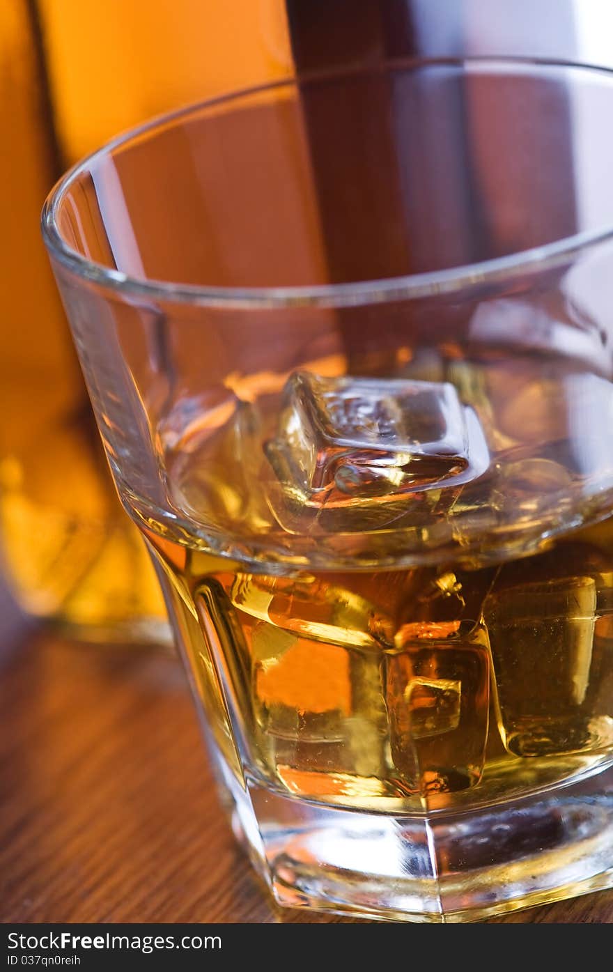 Whiskey glass and bottle on wooden counter