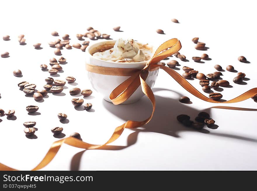 Cup of coffee with cream and golden ribbon