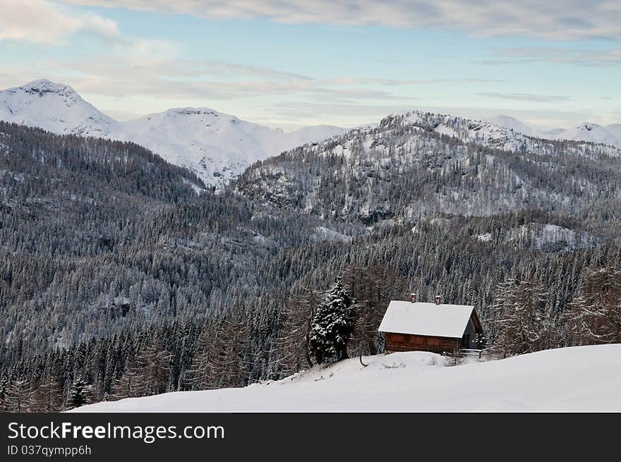 Mountain hut in winter with forest and mountains in the background. Mountain hut in winter with forest and mountains in the background