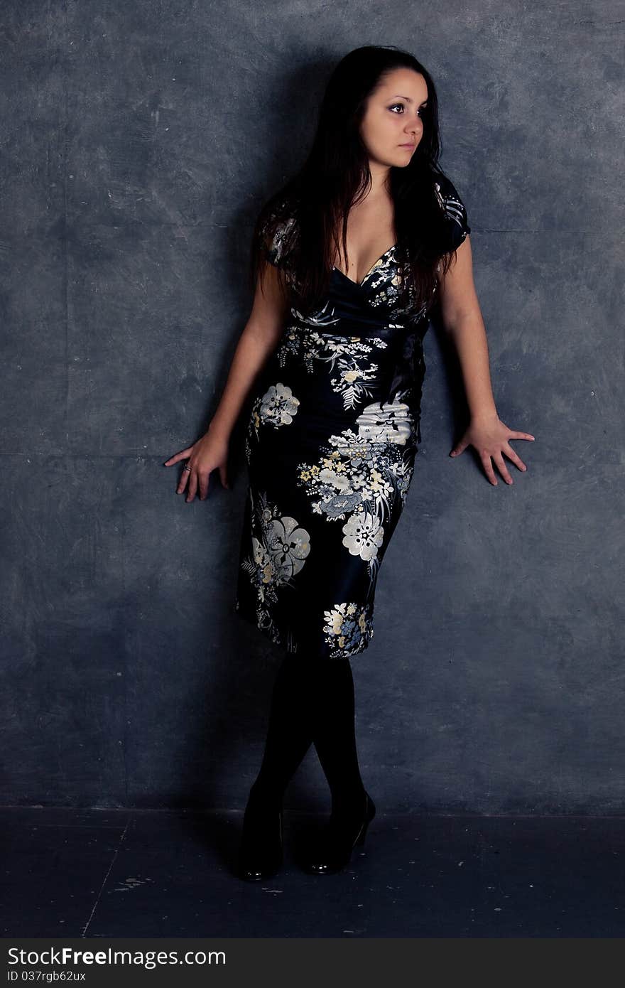 Girl in dress standing near a gray wall