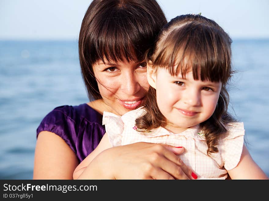 Mother hugging her daughter on sea background