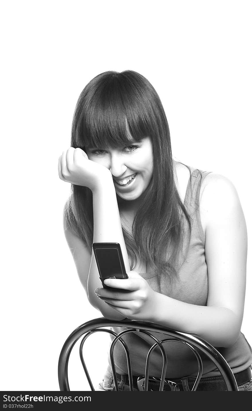 The young girl sitting on a chair with a mobile phone in a hand