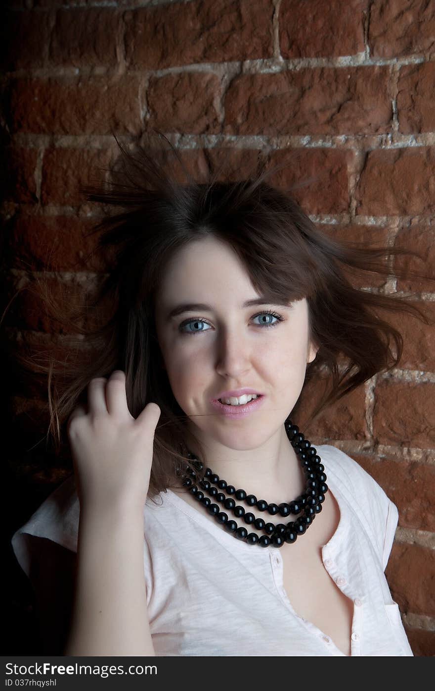 The young girl against a wall with a flying hair