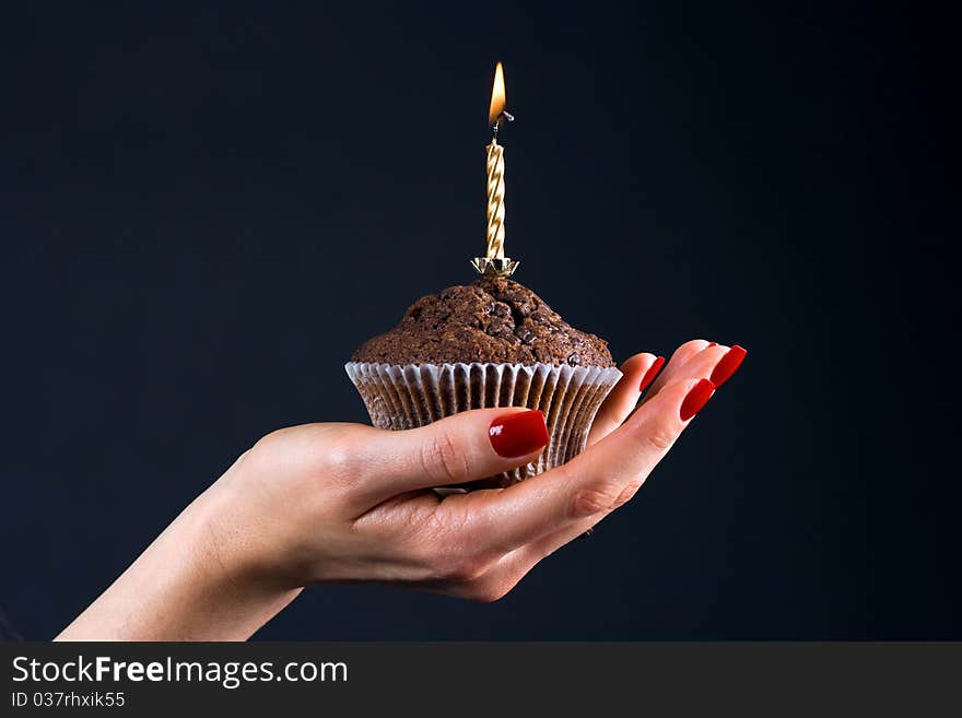 Muffin with a candle in the palm of a girl