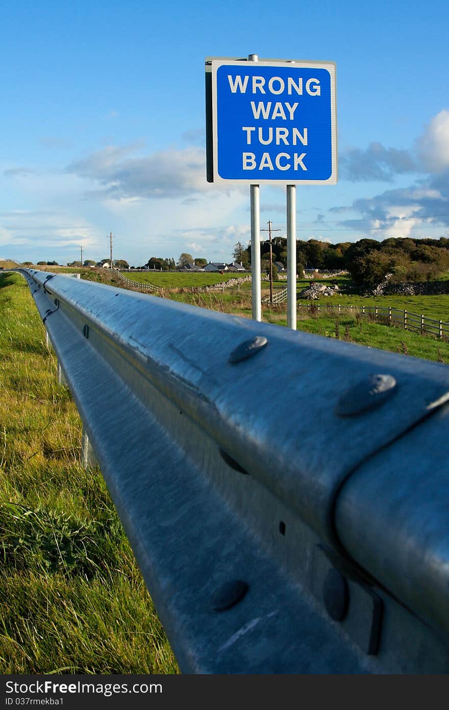 Road sign ' Wrong Way' and blue sky with clouds