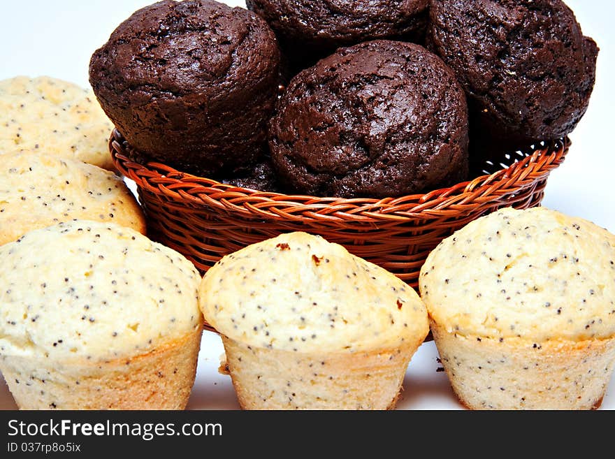 Basket filled with chocolate muffins and lemon poppy seed muffins in front on white background. Basket filled with chocolate muffins and lemon poppy seed muffins in front on white background