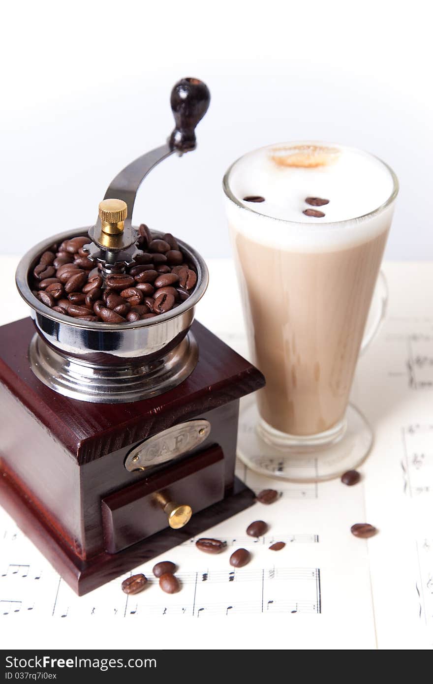 Coffee cup with coffee grinder on sheet music close up. Coffee cup with coffee grinder on sheet music close up