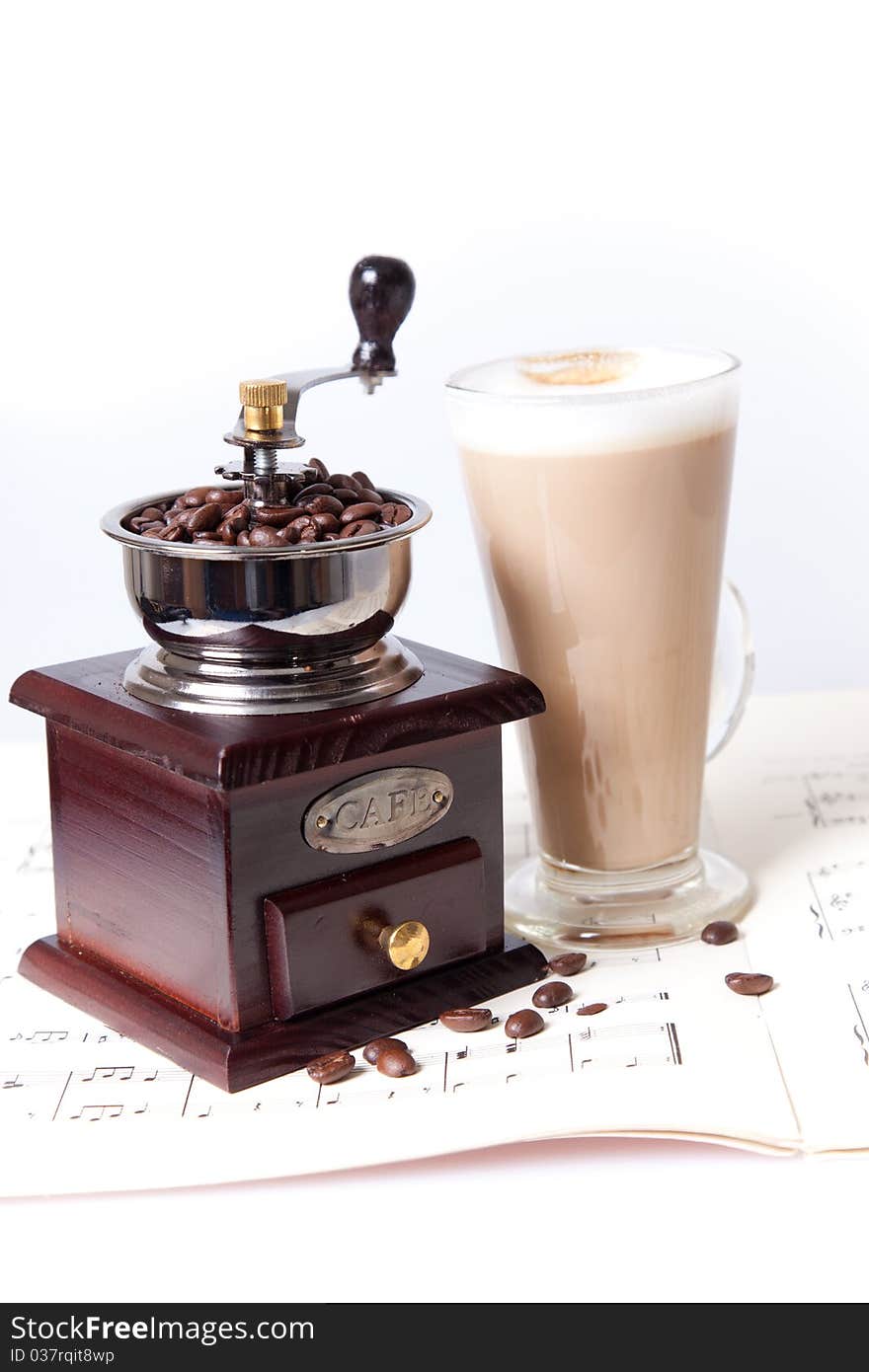 Coffee cup with coffee grinder on sheet music close up. Coffee cup with coffee grinder on sheet music close up