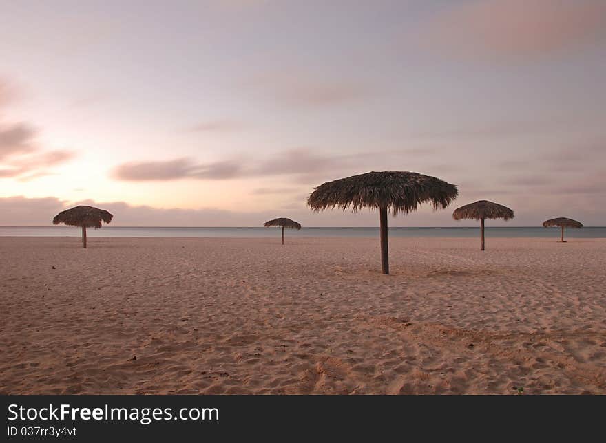 Beautiful white Cuban beach with parasols and turquoise sea at sunset. Beautiful white Cuban beach with parasols and turquoise sea at sunset