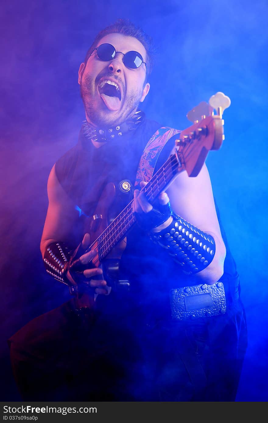 Heavy metal musician  is playing electrical guitar. Shot in a studio. Heavy metal musician  is playing electrical guitar. Shot in a studio.