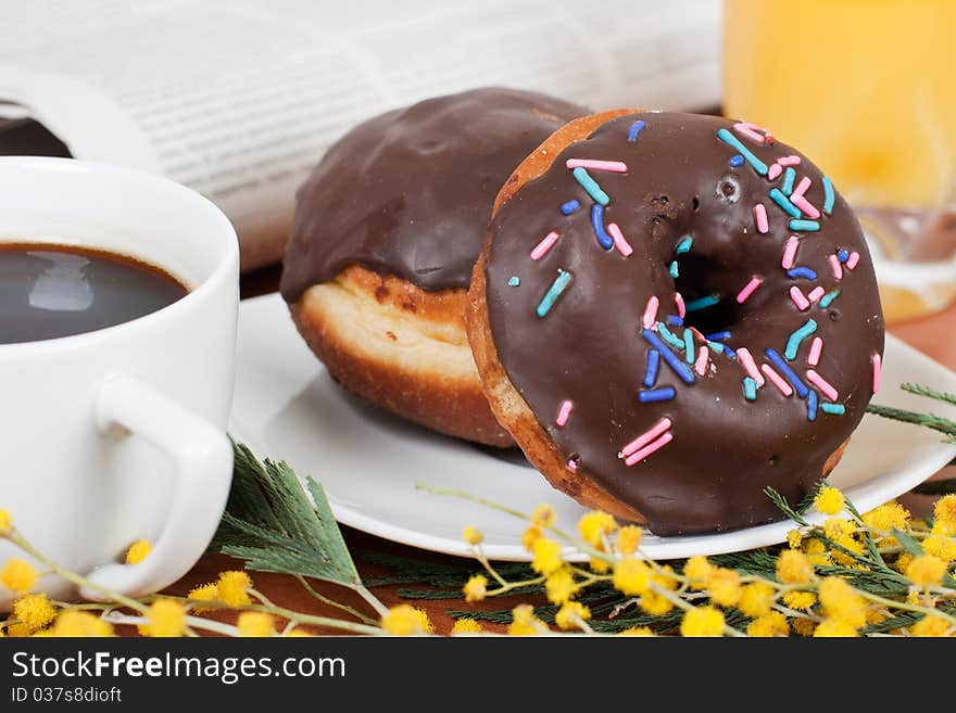 Chocolate donut served with coffee and orange juice. Chocolate donut served with coffee and orange juice.