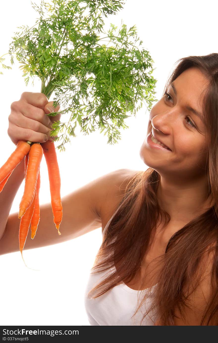 Young brunette healthy woman holding in right hand bunch fresh orange organic carrots with green leaves from the garden isolated on a white background. Young brunette healthy woman holding in right hand bunch fresh orange organic carrots with green leaves from the garden isolated on a white background