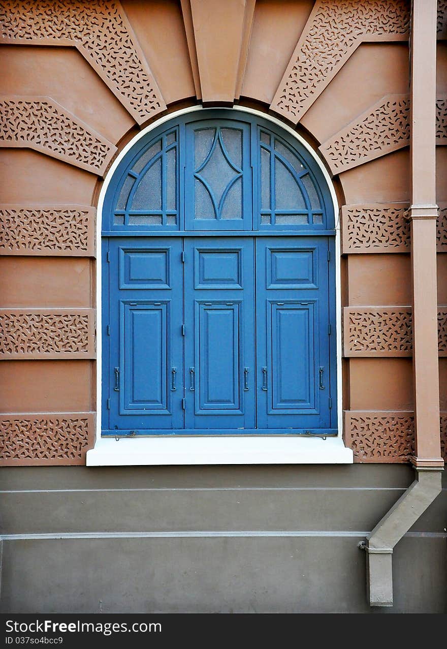 Blue window on brown wall of royal Thai palace in Bangkok, Thailand