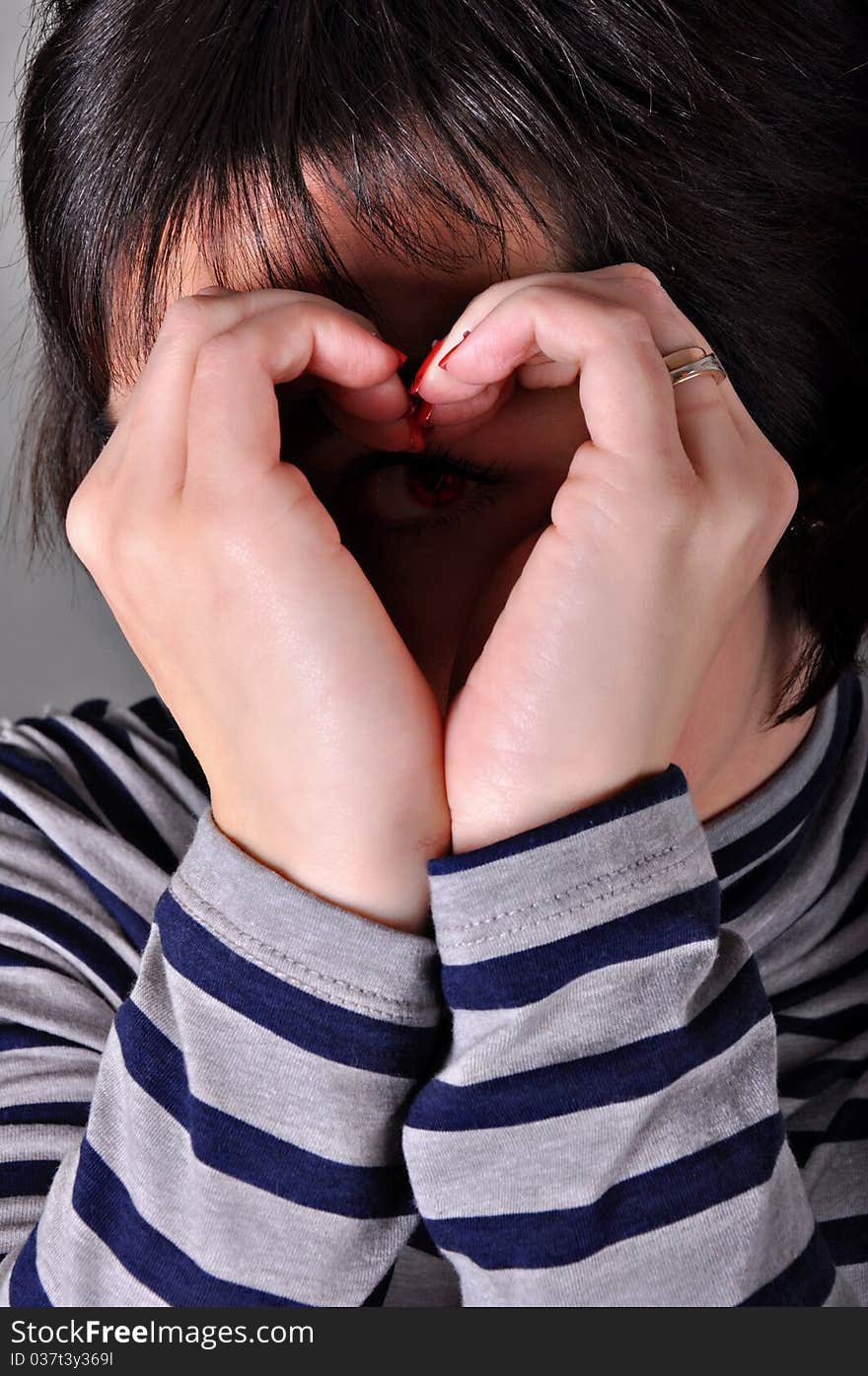 Young beautiful smiling girl making a heart with her hand