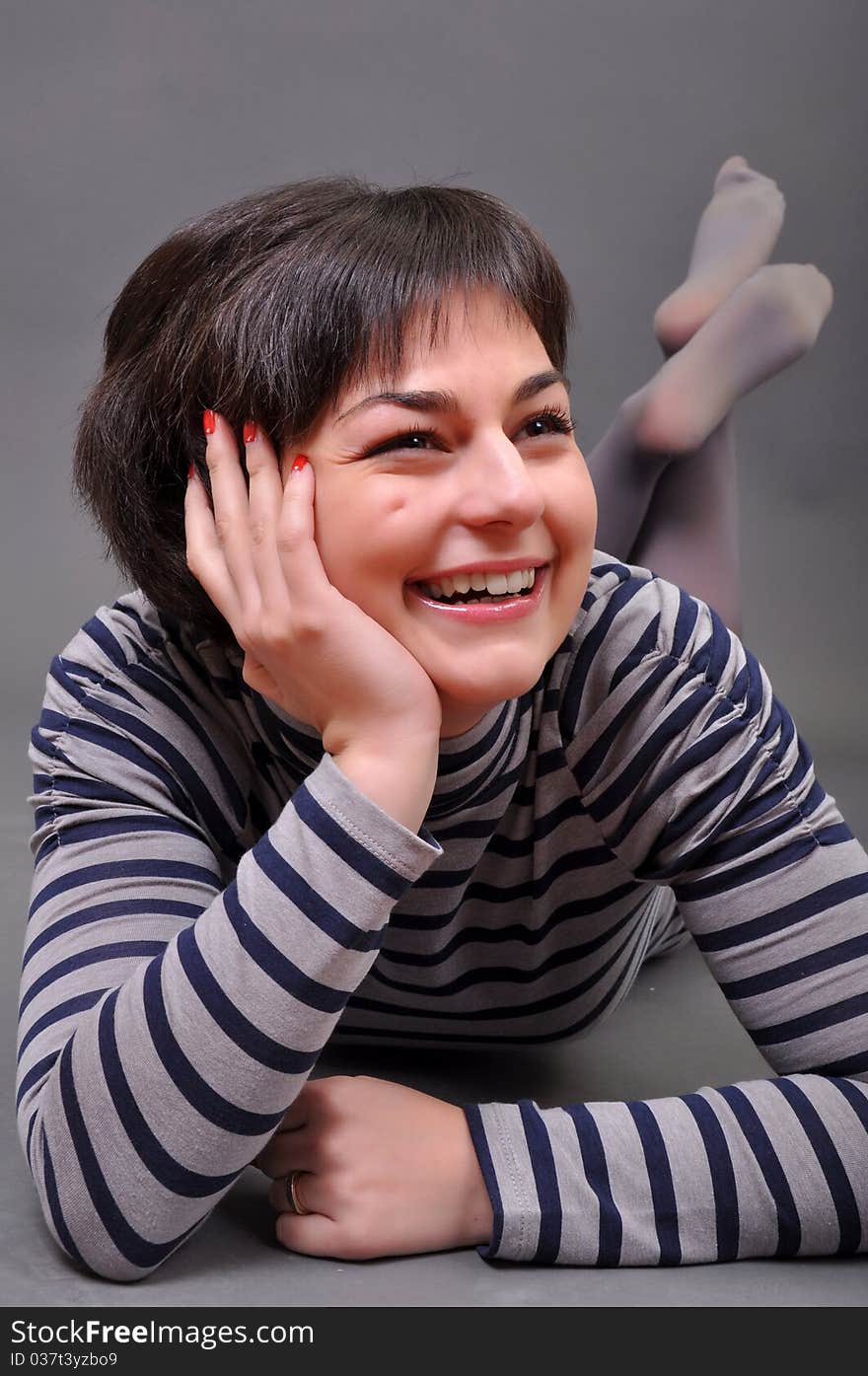 Casual woman smiling on the floor isolated over a white background