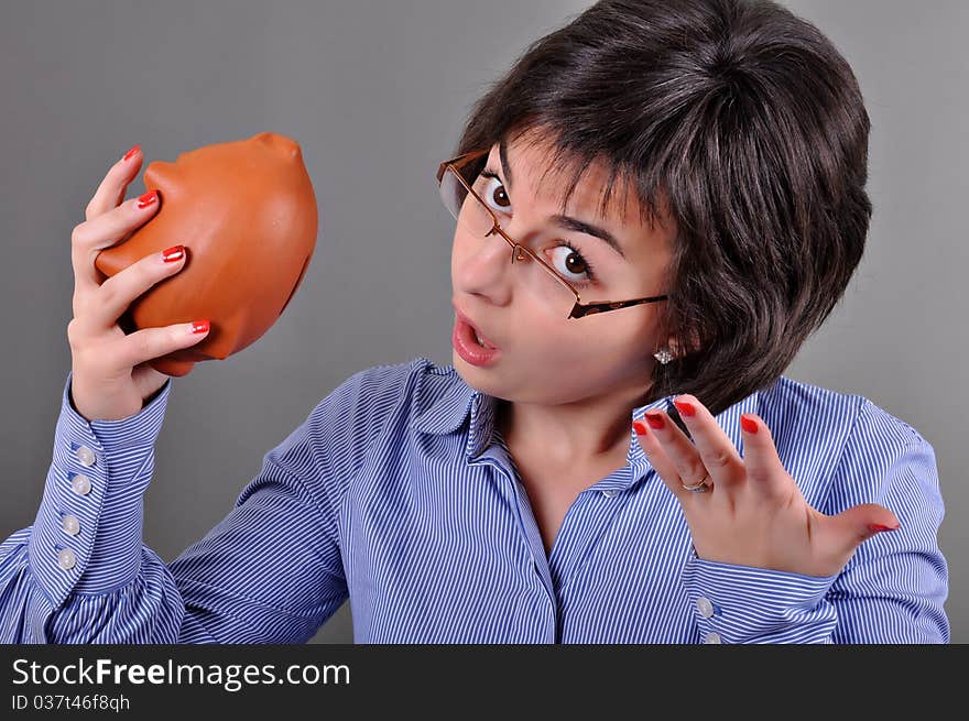 Young woman trying to get money from her piggy bank