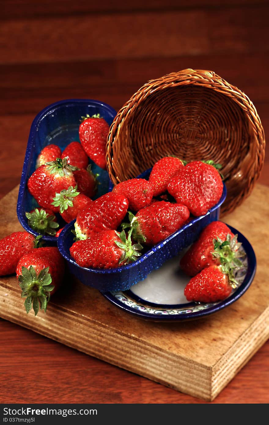 Small baskets with strawberries on chopping board