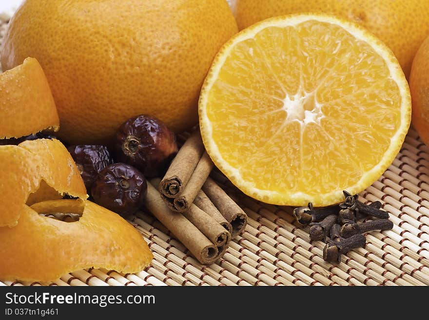 Oranges with cinnamon and spices on bamboo pad