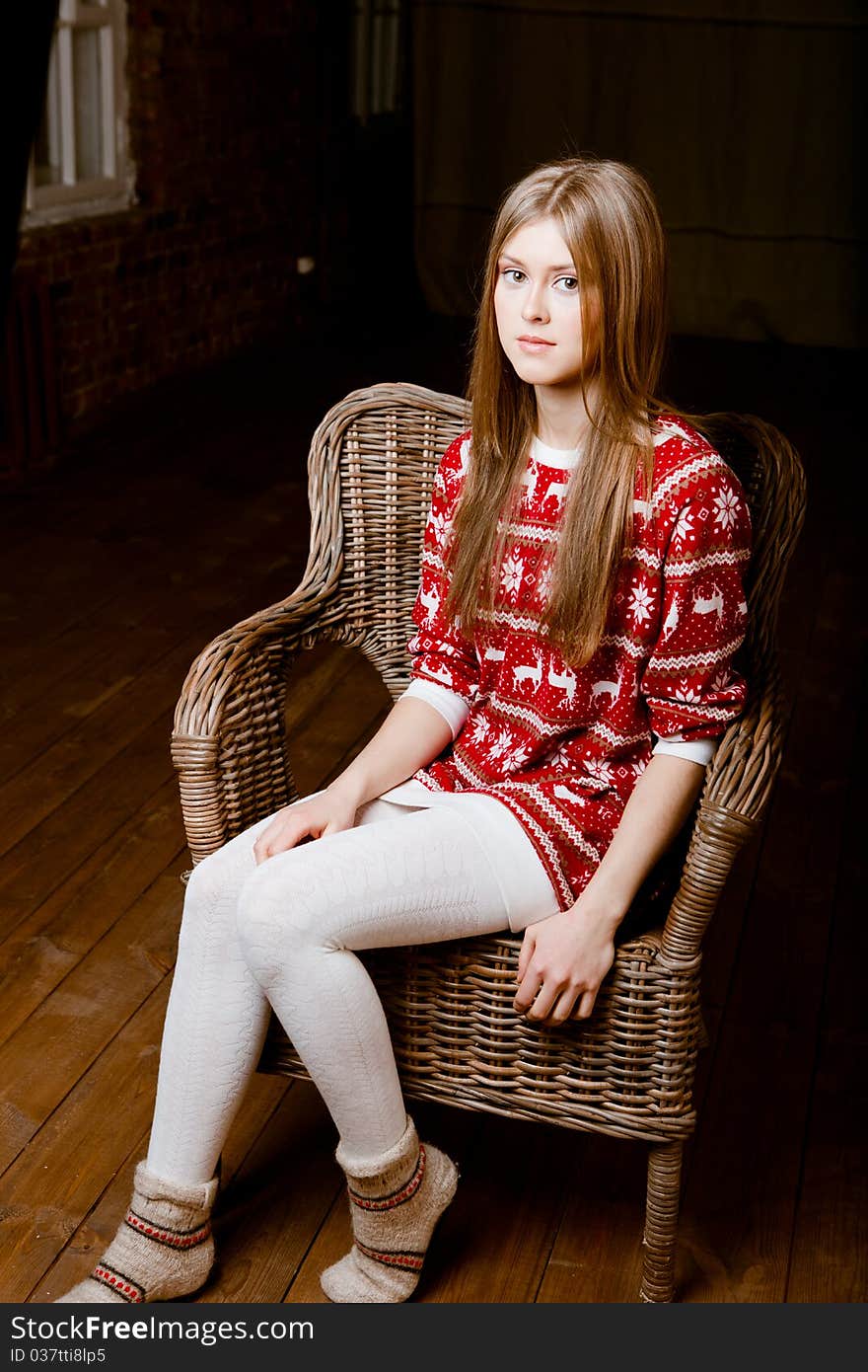 Cute woman sits in a chair wearing a sweater with the reindeer