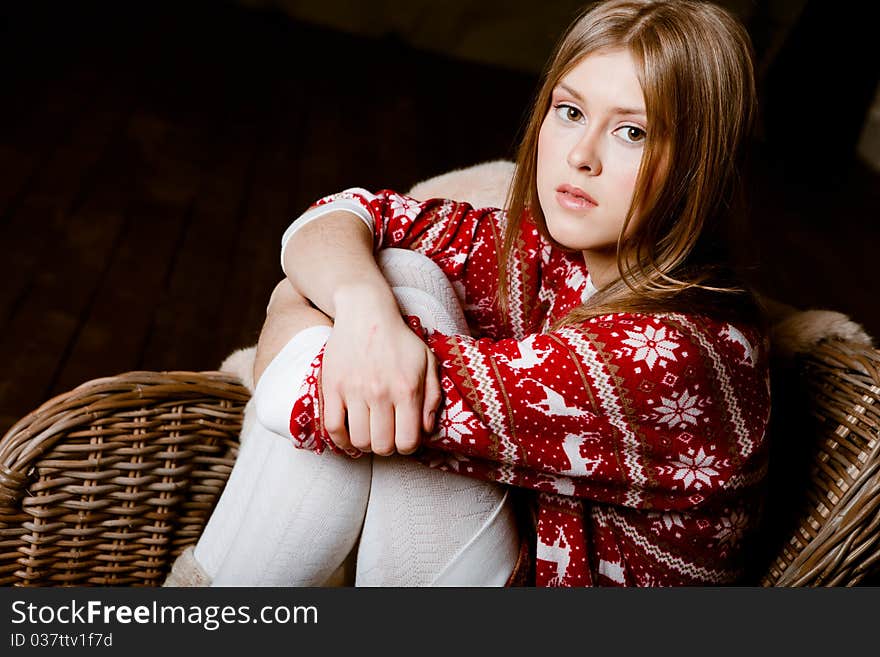 Cute woman sits in a chair wearing a sweater with the reindeer