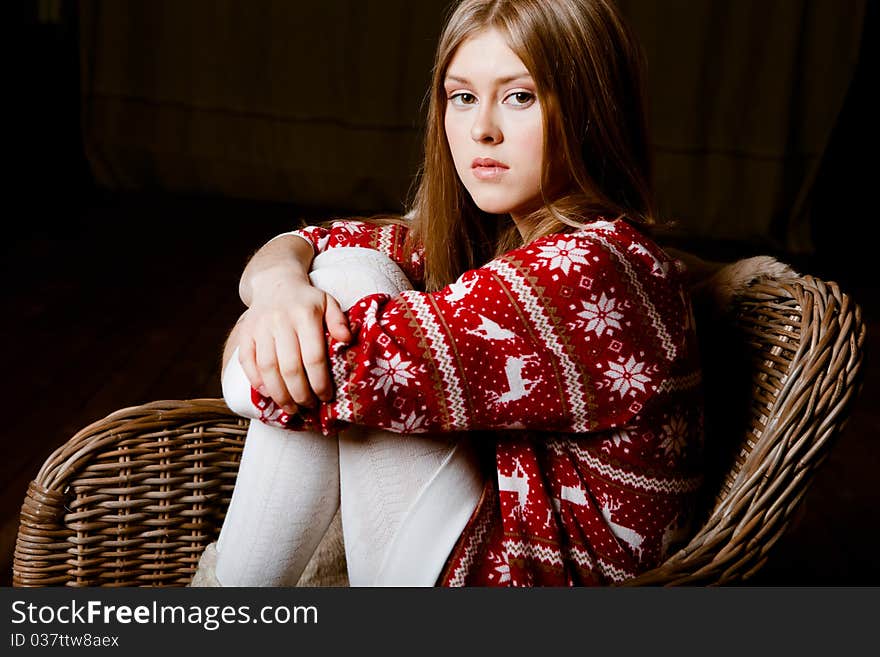 Cute woman sits in a chair wearing a sweater with the reindeer