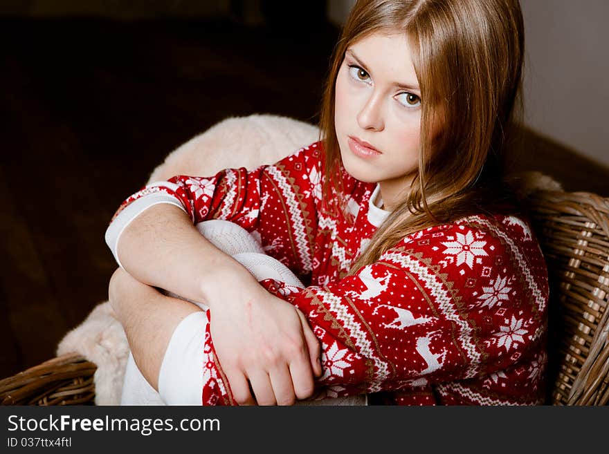 Cute woman sits in a chair wearing a sweater with the reindeer