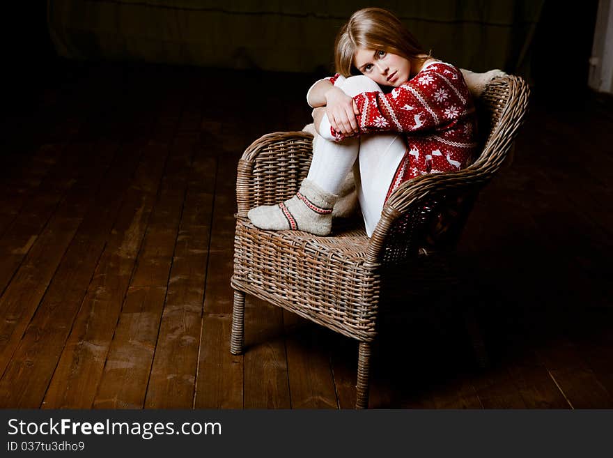 Cute woman sits in a chair wearing a sweater with the reindeer