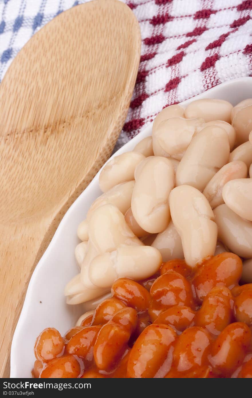 White canned beans in a white ceramic dish with red sauce. White canned beans in a white ceramic dish with red sauce.