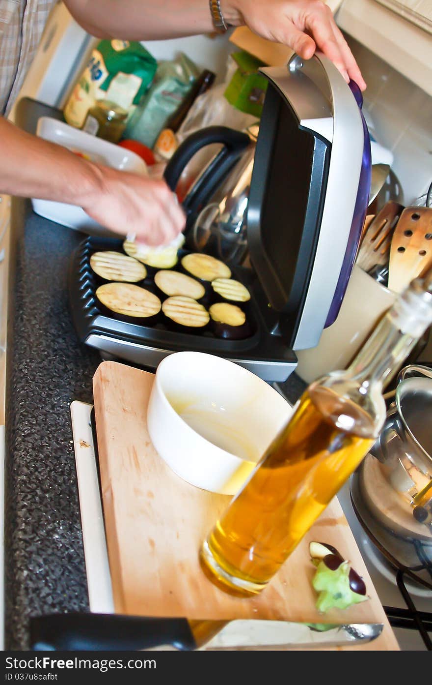 Man oiling aubergines to grill them. Man oiling aubergines to grill them