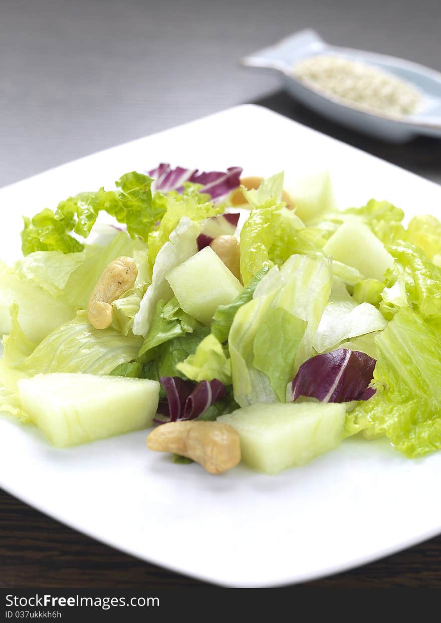 A salad made of lettuce,cabbage,melon and cashius peanuts. A salad made of lettuce,cabbage,melon and cashius peanuts