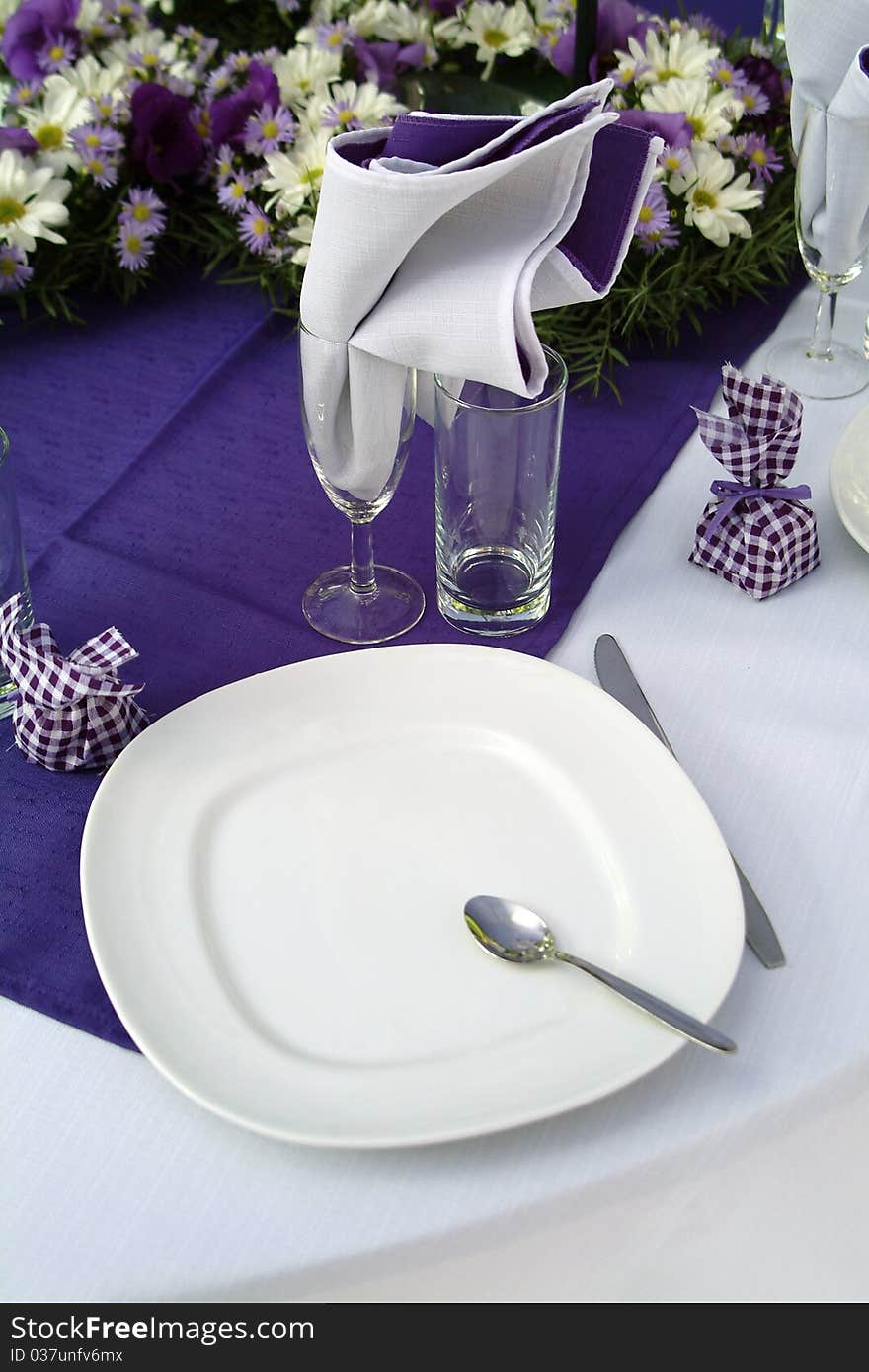 Purple place setting with white cutlery and white and purple daisies. Purple place setting with white cutlery and white and purple daisies