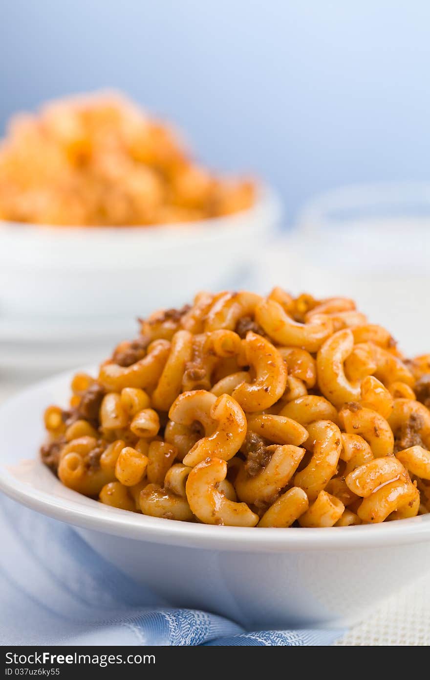 Macaroni with tomato meat sauce. Blue background. Shallow depth of field. Macaroni with tomato meat sauce. Blue background. Shallow depth of field.