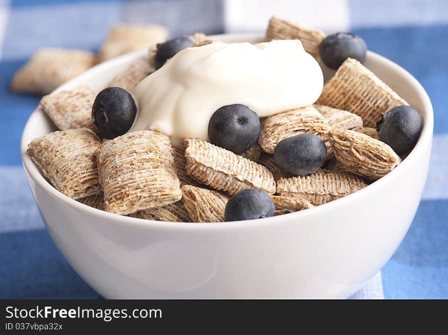 Wholegrain shredded wheat with creme fraiche and blueberries in a bowl