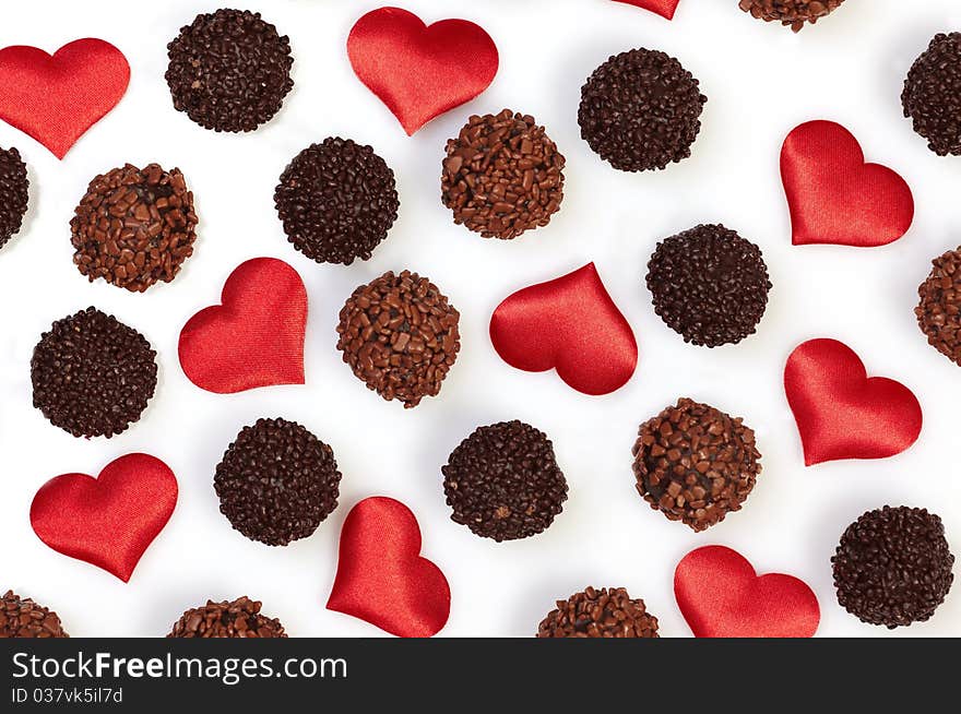 Chocolate truffles and heart shapes on white background