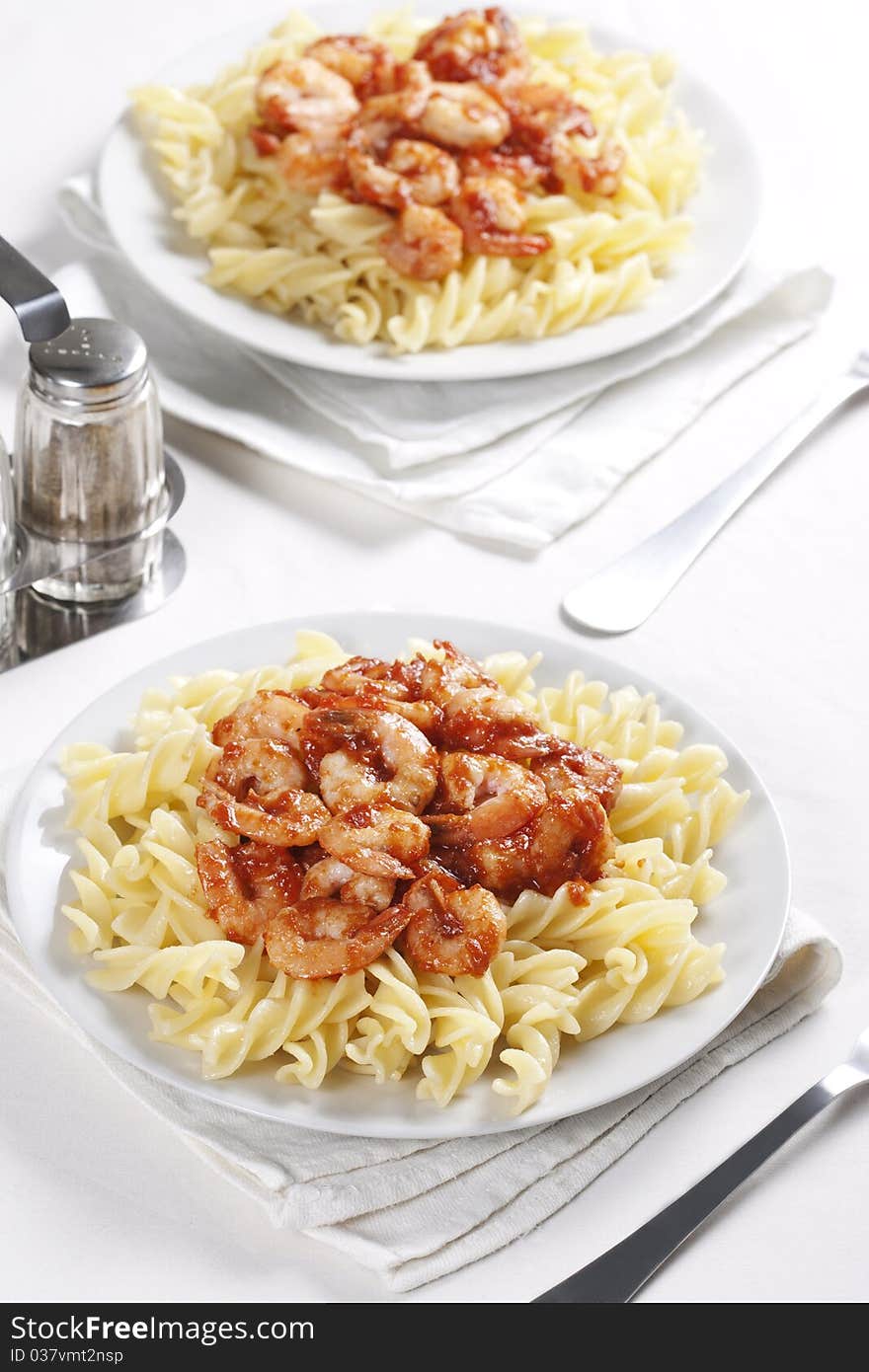 Two plates of pasta with tomato and shrimps