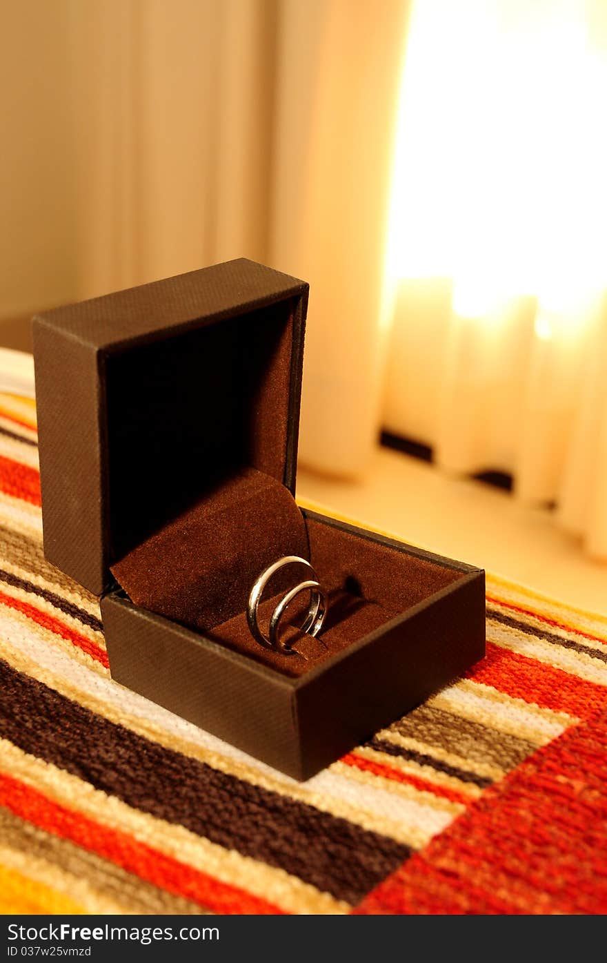 Wedding rings, in a brown box, on the bed. Wedding rings, in a brown box, on the bed