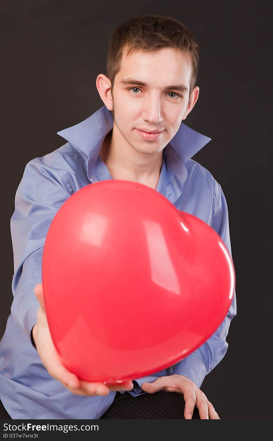 Young guy holding a red heart-shaped balloon