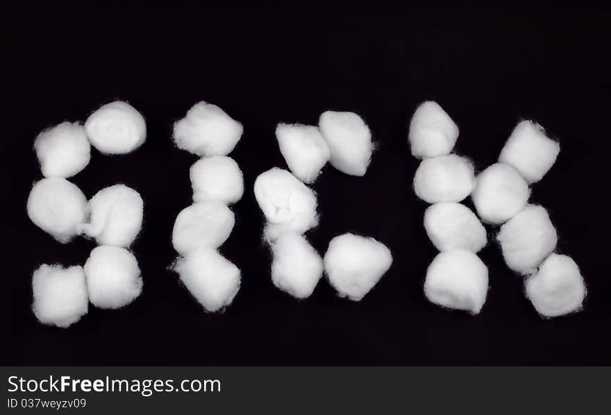 The word 'Sick' written with cotton balls. Isolated on black.