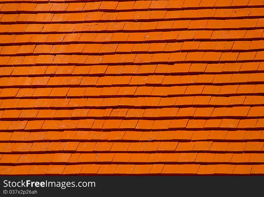 Image of a slanting roof made of wooden tiles and painted bright red. Image of a slanting roof made of wooden tiles and painted bright red