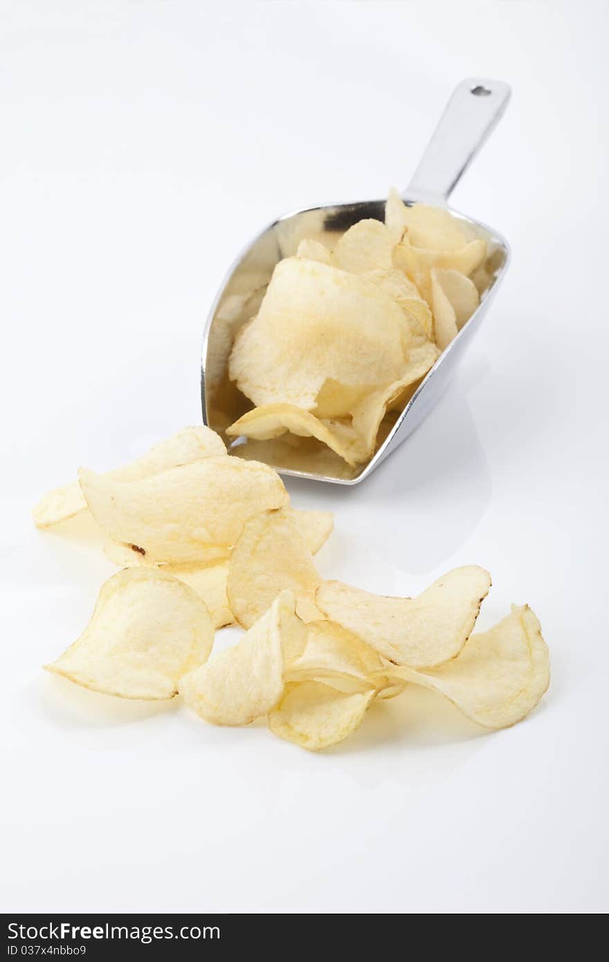 Golden potato chips on and in front of a shovel isolated on a white background