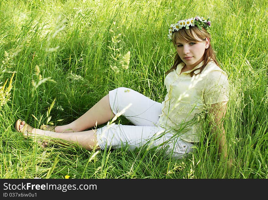 Young girl into the wreath on the grass. Young girl into the wreath on the grass